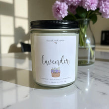 Load image into Gallery viewer, Lavender candle with a label on a marble surface, flowers in the background
